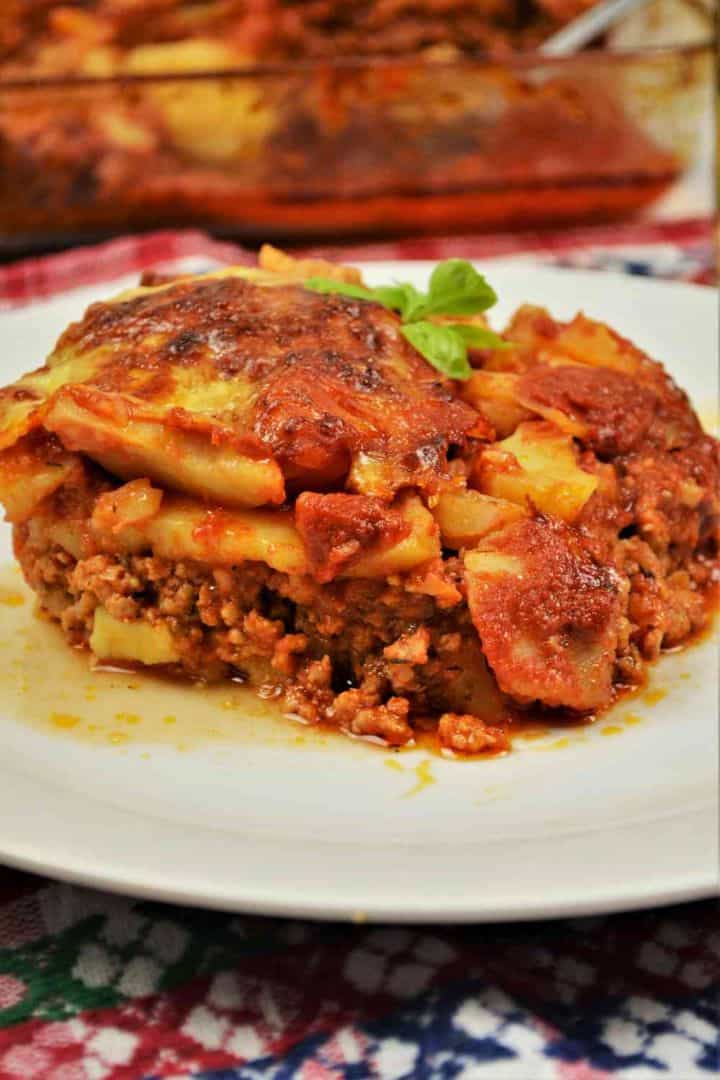 Easy Potato Moussaka Recipe-Served on Plate With a Fork A square slice of baked potato moussaka showing layers of tender potatoes, minced pork, and a golden melted cheese crust.