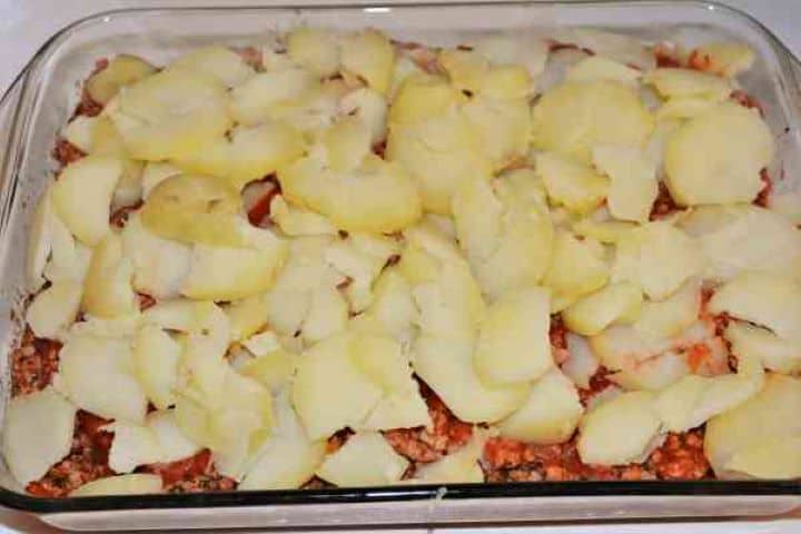 Easy Potato Moussaka Recipe-Sliced Potatoes on Mince Meat in Baking Tray Arranging the second layer of sliced potatoes over the savory meat filling.