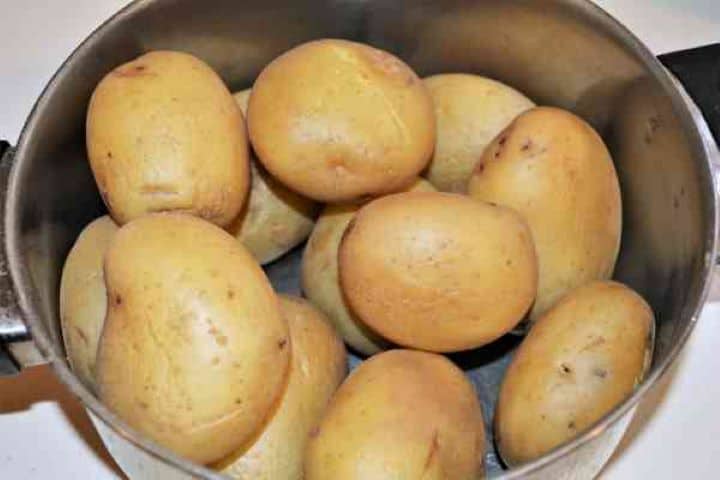 Easy Potato Moussaka Recipe-Boiled and Cooled Potatoes in the Pot Whole unpeeled potatoes boiled tender in a pot of salted water.