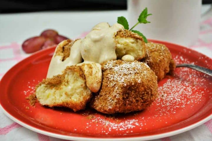 Best Cottage Cheese Dumplings-Served on Plate With Cream Fresh Warm Hungarian Túrógombóc garnished with sweet vanilla cream and ground cinnamon, ready to eat.