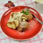 Authentic Hungarian cottage cheese dumplings (Túrógombóc) served on a red plate with sweet vanilla sour cream.