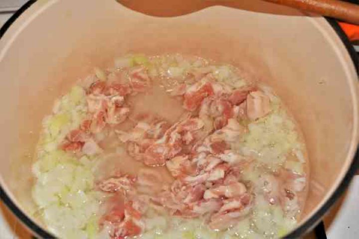Turkey Cabbage Stew Recipe-Frying Chopped Onion and Bacon in the Pot Cooking diced smoked bacon and red bell pepper with sautéed onion in a pot.
