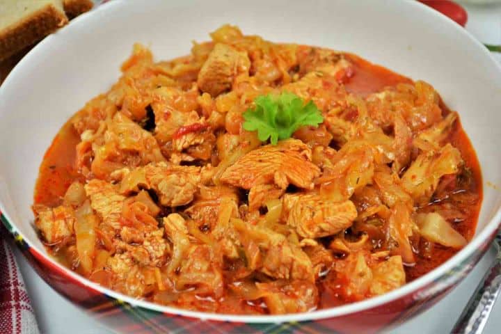 Turkey Cabbage Stew Recipe-Served in Bowl With Bread and Sour Cream Close-up of tender cubed turkey and braised cabbage in savory tomato dill sauce.