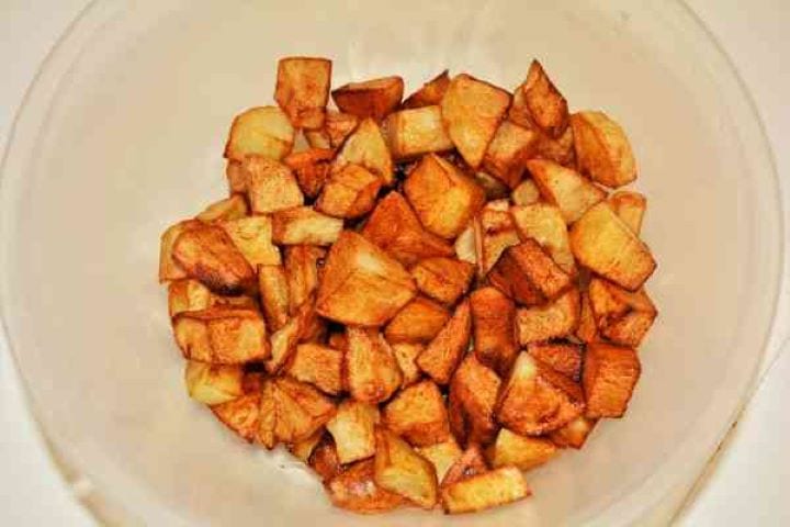 Brasov Roast Recipe-Fried Potatoes Cut in Cubes in the Bowl Close-up texture of perfectly fried, golden-brown crispy potato cubes draining lightly in a bowl.