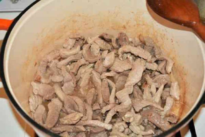 Brasov Roast Recipe-Frying Pork Strips in the Pot Diced smoked bacon rendering its fat alongside seared golden-brown pork shoulder cubes in a pot.