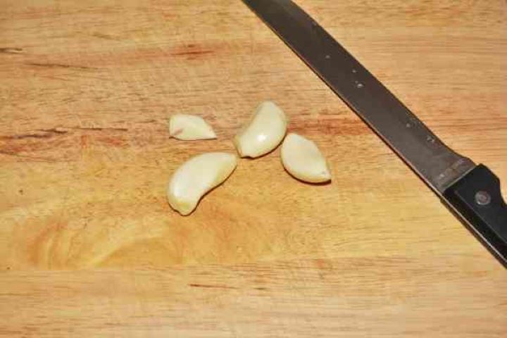 Pan-Fried Rainbow Trout Recipe-Four Peeled Garlic Cloves Four Peeled Garlic Cloves on the Chopping Board