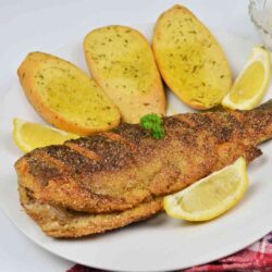 Pan-Fried Rainbow Trout Recipe-Fried Trout Served on Plate With Lemon and Garlic Bread
