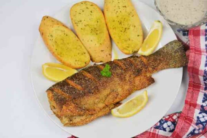 Pan-Fried Rainbow Trout Recipe-Fried Trout Served on Plate With Lemon and Garlic Bread Pan-Fried Rainbow Trout Served on Plate With Lemon Slices and Garlic Bread