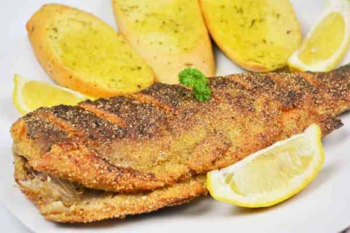 Pan-Fried Rainbow Trout Recipe-Fried Trout Served on Plate With Lemon and Garlic Bread Pan-Fried Rainbow Trout Served on White Plate With Lemon and Three Slice Garlic Bread