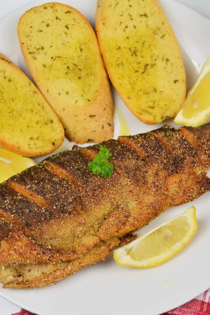 Pan-Fried Rainbow Trout Served on Plate With Lemon and Garlic Bread
