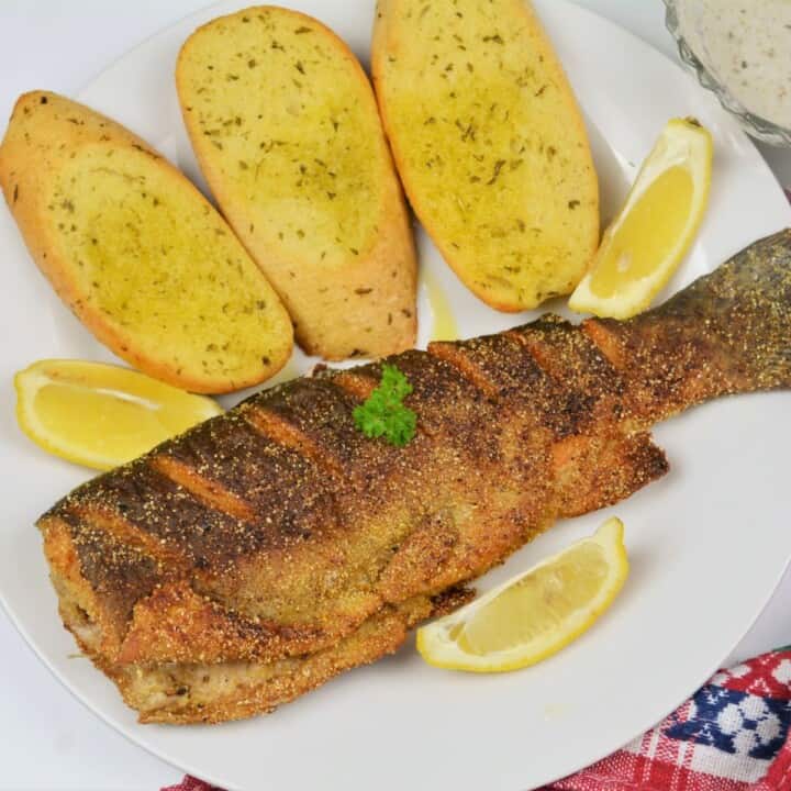 Pan-Fried Rainbow Trout Served on Plate With Lemon and Garlic Bread