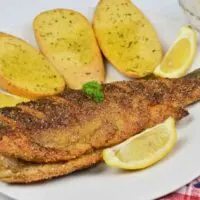Pan-Fried Rainbow Trout Recipe-Fried Trout Served on Plate With Lemon and Garlic Bread