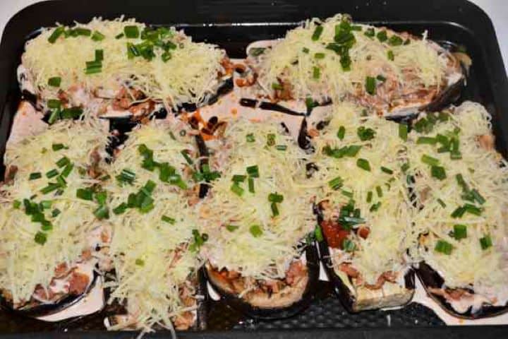 Stuffed Aubergines Recipe-Chopped Chives Over the Stuffed Aubergines Stuffed eggplants topped with a generous layer of grated cheddar cheese and a sprinkle of fresh green chives before going into the oven.