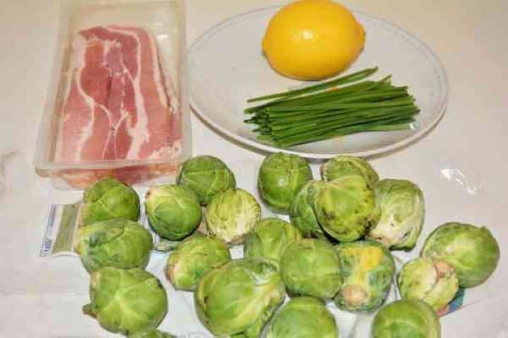 Brussels Sprouts With Lemon-Brussels Sprouts, Bacon, Lemon and Chives on the Table Ingredients for making lemon bacon Brussels sprouts: fresh sprouts, sliced smoked bacon, a whole lemon, and a bunch of fresh chives.