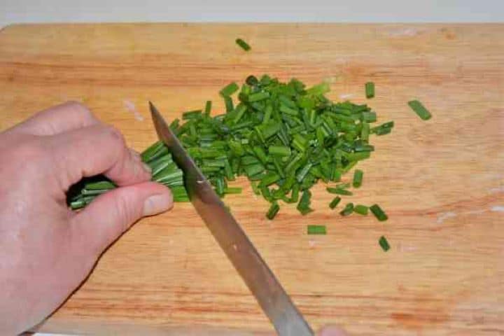 Brussels Sprouts With Lemon-Chopping the Chives on the Chopping Board Finely chopping a bunch of fresh green chives with a chef's knife.
