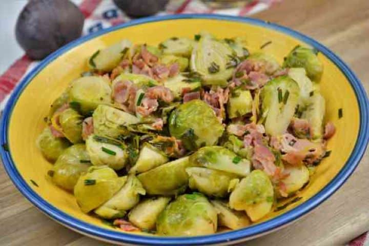Brussels Sprouts With Lemon-Served in the Bowl on the Chopping Board Warm Brussels sprouts with lemon and smoked bacon ready to serve on a wooden board.