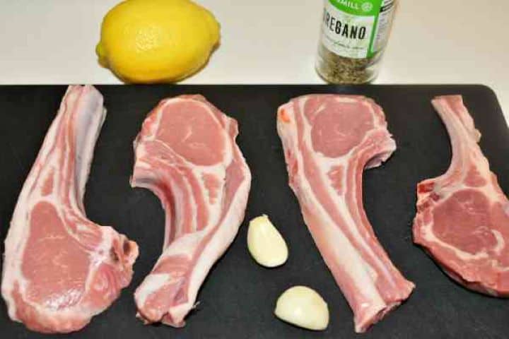 Greek Lamb Chops Recipe-Lamb Cutlets, Oregano, Lemon and Garlic Cloves Ingredients for Greek lamb chops including fresh lamb cutlets, whole garlic cloves, lemon halves, and dried Greek oregano.