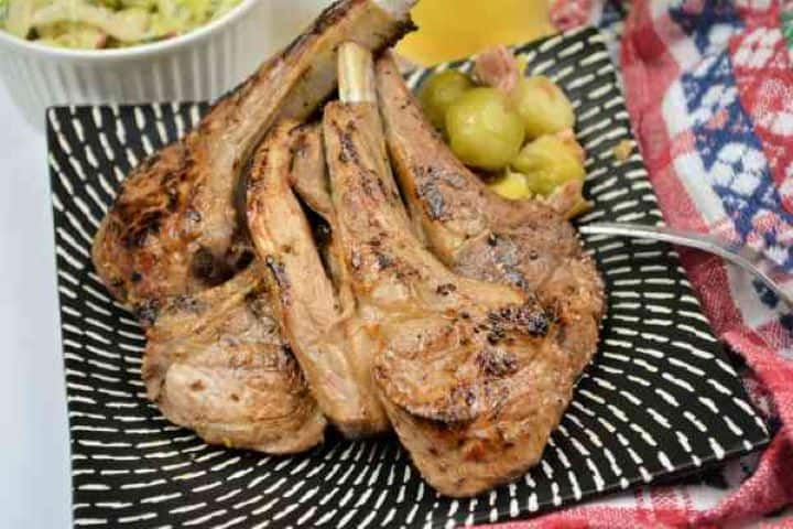 Greek Lamb Chops Recipe-Served on Plate With Brussels Sprouts and a Glass of Beer Juicy pan-seared Greek lamb chops garnished with fresh lemon wedges, flaky sea salt, and a sprinkle of dried oregano on a rustic serving platter.