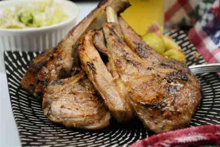 Greek Lamb Chops Recipe-Served on Plate With Brussels Sprouts and a Glass of Beer Tender Greek lamb cutlets served for dinner alongside a crisp Mediterranean salad, lemon wedges, and cold beer.