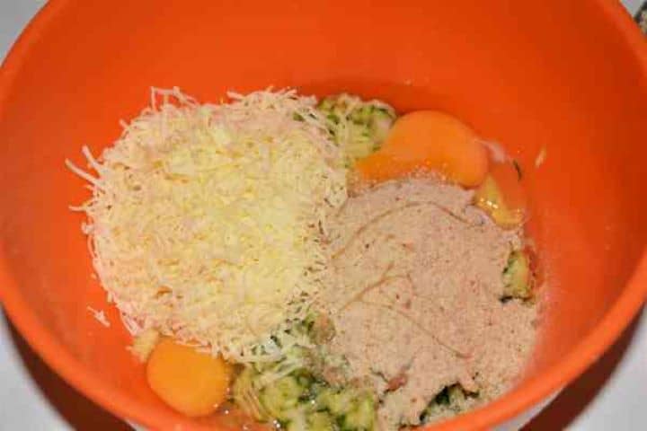 Zucchini Balls Recipe-Eggs, Breadcrumbs and Grated Cheddar Over the Grated Zucchini and Kapia Pepper in the Bowl Whole eggs, breadcrumbs, chopped parsley, and grated cheddar cheese added over the squeezed vegetables in a bowl.