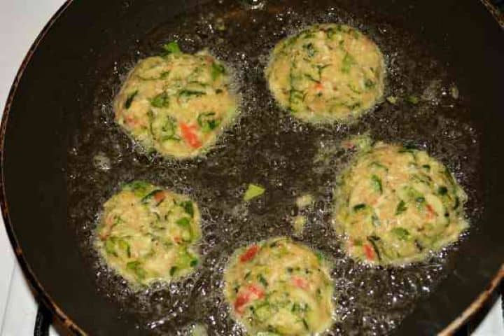 Zucchini Balls Recipe-Unfried Zucchini Balls on the Chopping Board Uncooked zucchini balls placed in hot sunflower oil in a non-stick frying pan.