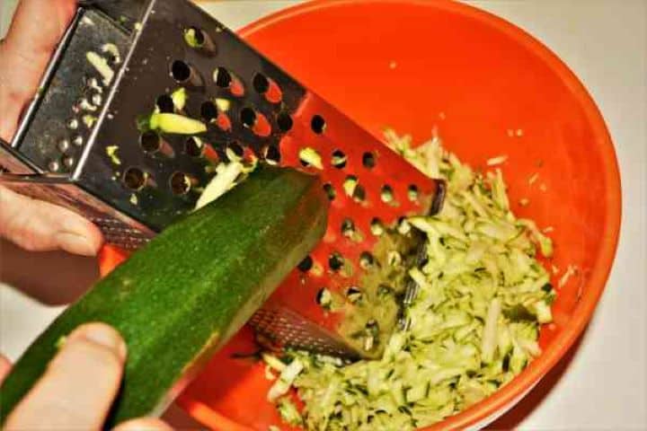 Zucchini Balls Recipe-Grated Zucchini in the Bowl Freshly grated unpeeled green zucchini in an orange mixing bowl.