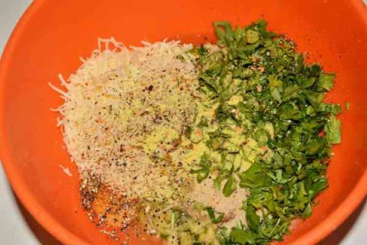 Zucchini Balls Recipe-Seasoning the Eggs, Breadcrumbs, Grated Cheddar, Grated Zucchini and Kapia Pepper in the Bowl Black pepper, garlic powder, chilli flakes, and vegetable seasoning added to the zucchini ball ingredients.