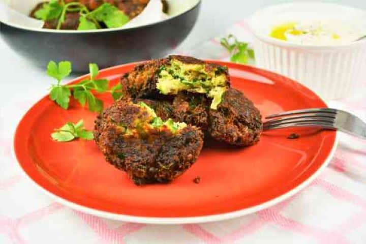 Zucchini Balls Recipe-Served on Plate With Yoghurt Dip Close-up of cheesy courgette balls showing the golden crust and herbs with dipping sauce.