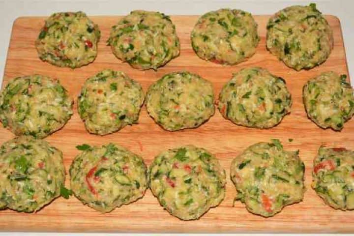 Zucchini Balls Recipe-Unfried Zucchini Balls on the Chopping Board Raw shaped zucchini balls slightly flattened on a wooden chopping board ready for frying.