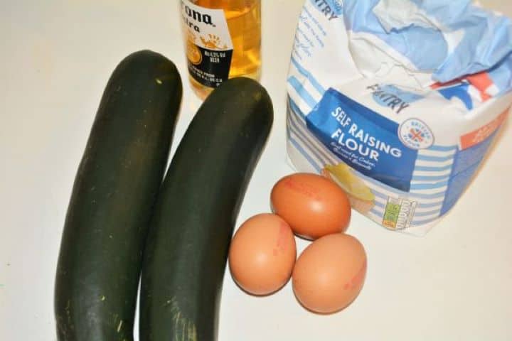 Battered Fried Zucchini-Zucchini, Eggs, Flour and Beer Fresh zucchini, eggs, self-raising flour, and beer laid out on a kitchen counter for making beer batter.