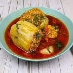 Two Hungarian Stuffed Peppers Served In Green Bowl With Sour Cream