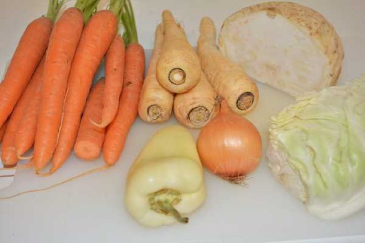 Semolina Dumplings Soup-Carrots, Parsley Roots, Celery Root, Onion, Pepper and Cabbage on the Chopping Board Peeled whole carrots, parsley roots, celeriac, onion, and sweet pepper for soup broth.