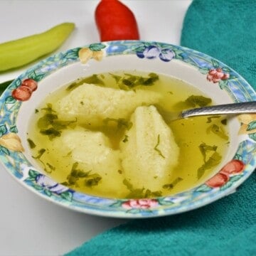 Authentic semolina dumplings soup garnished with fresh parsley and served with a hot chilli pepper.