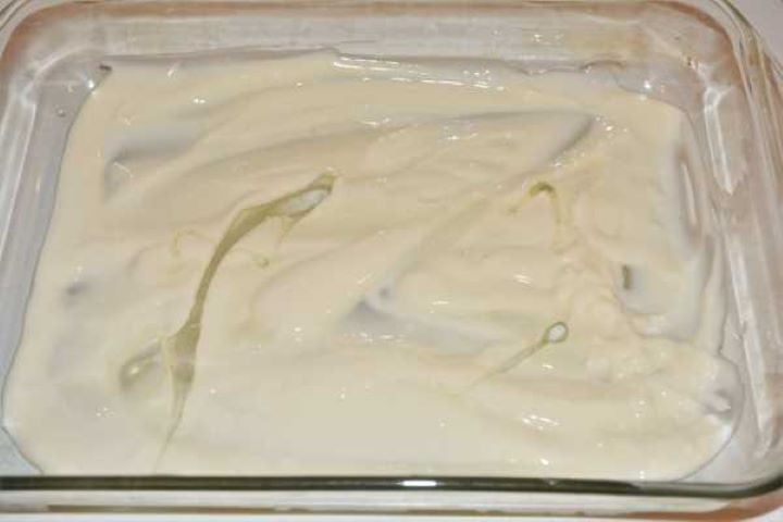 Turkey Lasagna With White Sauce-Cheese Sauce and Oil on the Bottom of Oven Tray White cheese sauce and sunflower oil spread across the bottom of a glass baking dish.