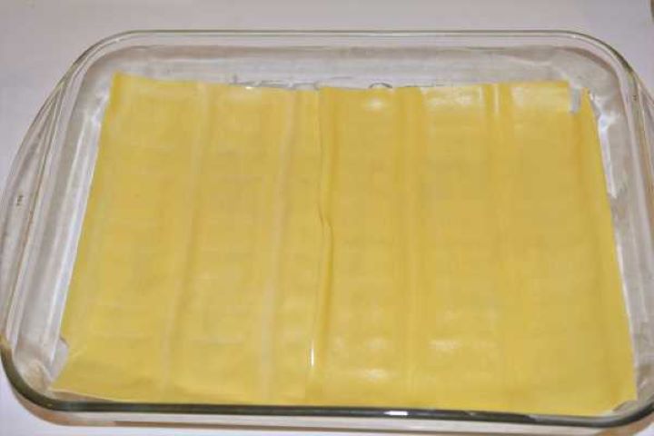 Turkey Lasagna With White Sauce-First Two Lasagna Sheets in the Baking Tray Two fresh lasagna sheets placed over the creamy white sauce base in a glass baking dish.