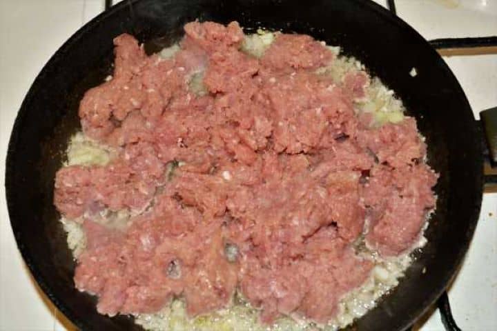 Turkey Lasagna With White Sauce-Ground Turkey on the Frying Chopped Onions in the Frying Pan Raw minced turkey added to softened onions in a hot frying pan.