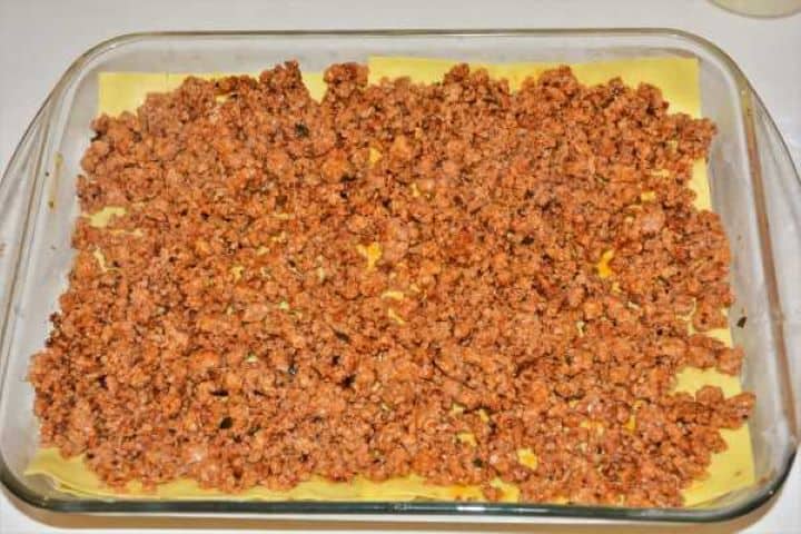 Turkey Lasagna With White Sauce-Cheese Sauce on the Second Filling Layer in the Baking Tray Spreading the remaining ground turkey filling across the middle pasta layer.