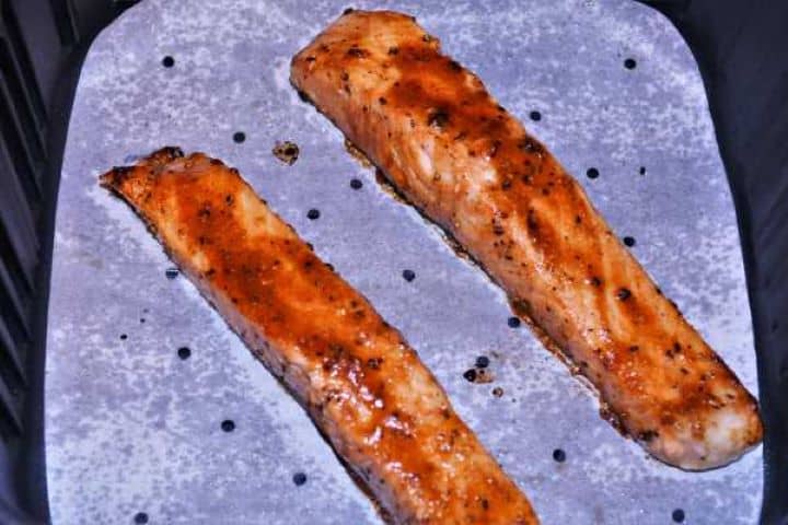 Fried Fully cooked, juicy teriyaki salmon with beautifully caramelized edges sitting inside an open air fryer basket.