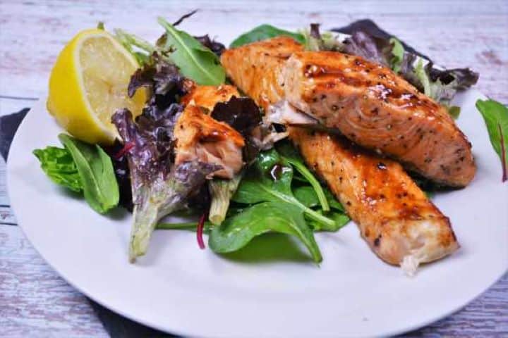 Served An easy weeknight dinner featuring glossy air fryer salmon teriyaki served fresh with lemon wedges and a side salad.