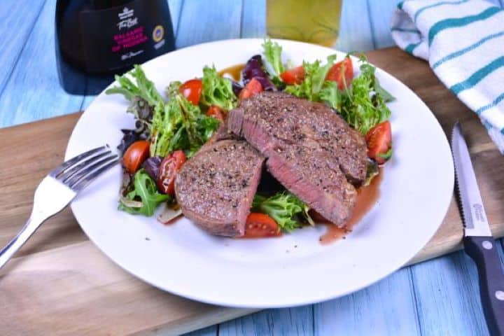 Ribeye Steak in Air Fryer-Served on Plate With Lettuce and Tomatoes Salad Tender cooked air fryer ribeye steak served on a plate with mixed greens, cherry tomatoes, and a cold beer.