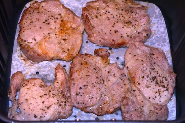 Pork Steak in Air Fryer-Fried Pork Steaks in the Air Fryer Basket Golden brown seared pork shoulder steaks cooked in the Cosori air fryer basket.