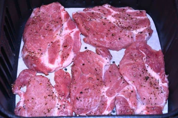 Pork Steak in Air Fryer-Salt and Pepper Seasoned Pork Shoulder Steaks in the Air Fryer Basket Salt and pepper seasoned pork steaks arranged in a single layer inside the air fryer basket.