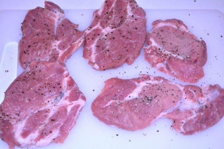 Pork Steak in Air Fryer-Salt and Pepper Seasoned Pork Shoulder Steaks on the Chopping Board Pork shoulder steaks seasoned with coarse sea salt and freshly ground black pepper on a cutting board.