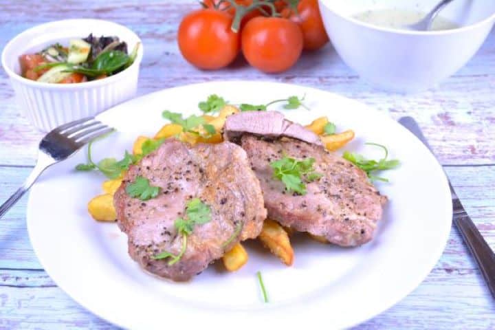 Pork Steak in Air Fryer-Served on Plate With French Fries Air fryer pork steak served on white plate with French fries.