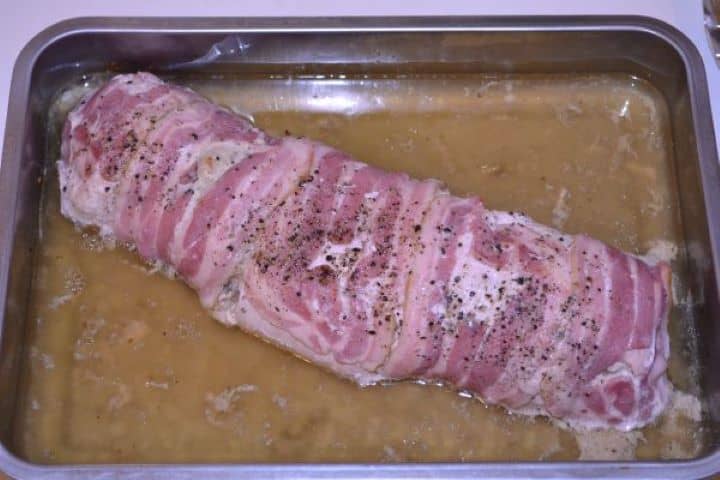 Stuffed Turkey Tenderloin Recipe-Baked Rolled Turkey Breast in the Baking Dish Stuffed turkey roll in a roasting dish after removing foil, showing the bacon beginning to brown.