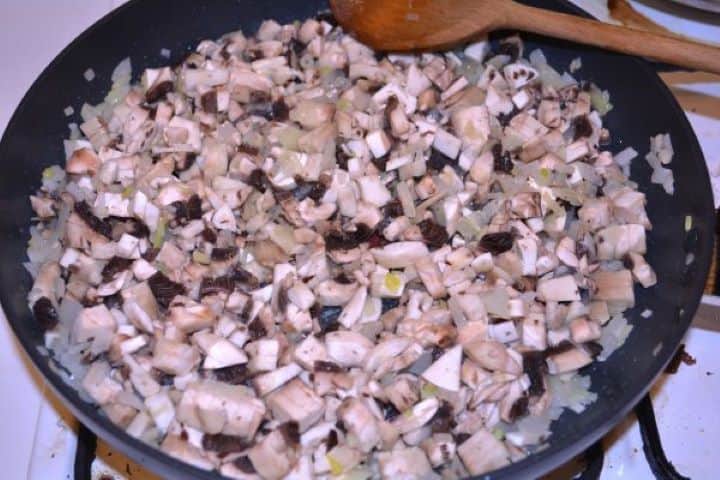 Stuffed Turkey Tenderloin Recipe-Frying Mushrooms and Chopped Onion in the Frying Pan Sautéing diced mushrooms and onions with dried marjoram, sea salt, and black pepper in a pan.