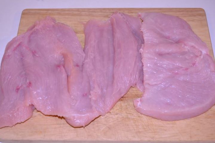 Stuffed Turkey Tenderloin Recipe-Opened Turkey Breast on the Chopping Board Butterflied raw turkey tenderloin opened flat like a book on a cutting board.