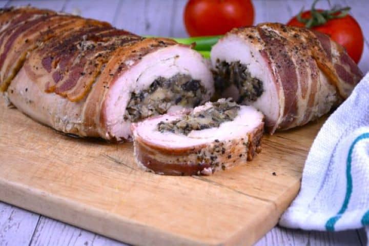 Stuffed Turkey Tenderloin Recipe-Sliced and Served on the Chopping Board Juicy stuffed turkey tenderloin pinwheels showing melted cheddar and mushroom filling, served with crisp spring onions and tomatoes on a rustic board.