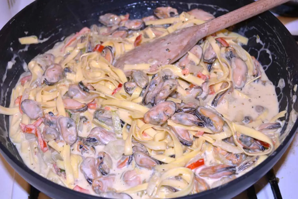 Frozen Mussels Recipe-Simmering Shelled Mussels With Tagliatelle Pasta and Vegetables in the Pan