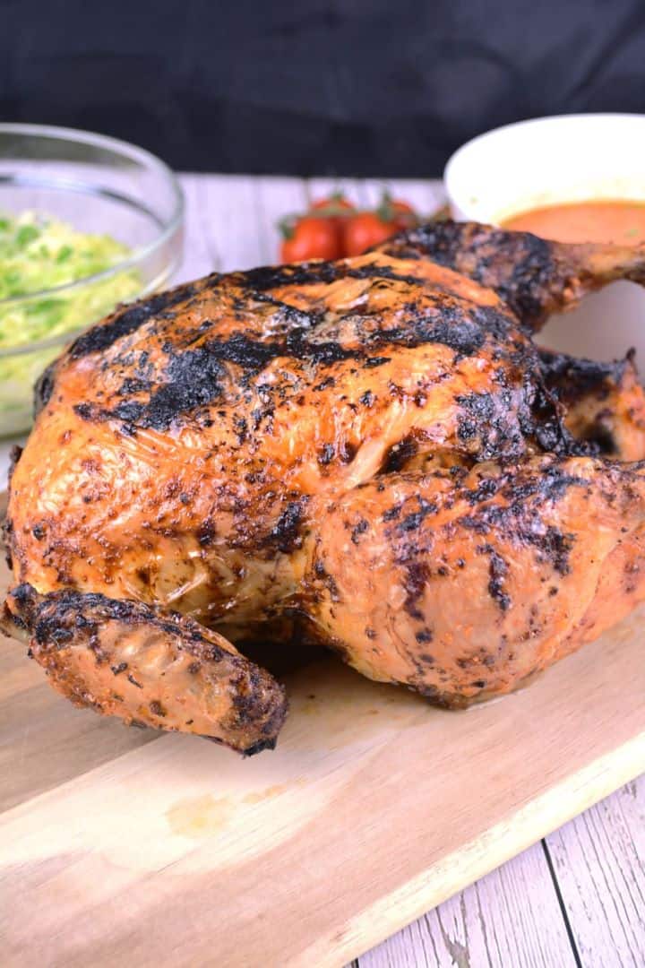 Golden brown crispy air fryer whole chicken with a rotisserie style glaze served on a chopping board.